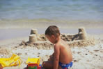Photo of boy on beach making sandcastles